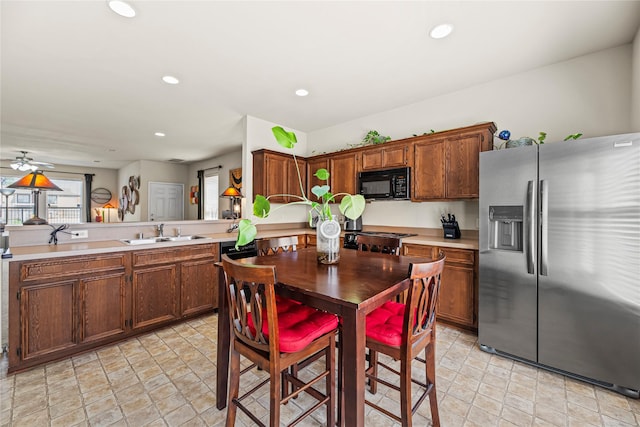 kitchen featuring recessed lighting, a sink, light countertops, stainless steel refrigerator with ice dispenser, and black microwave