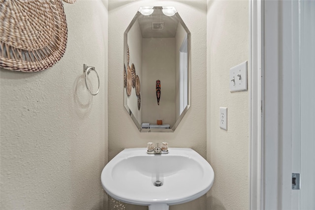 bathroom with a textured wall and a sink