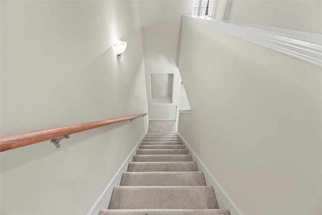 staircase featuring carpet flooring and baseboards