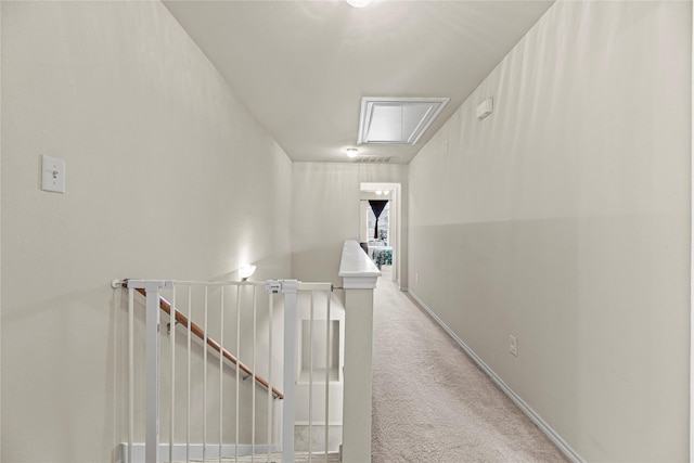 hallway featuring baseboards, an upstairs landing, attic access, and carpet flooring