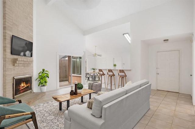 living area with a brick fireplace, light tile patterned flooring, and high vaulted ceiling