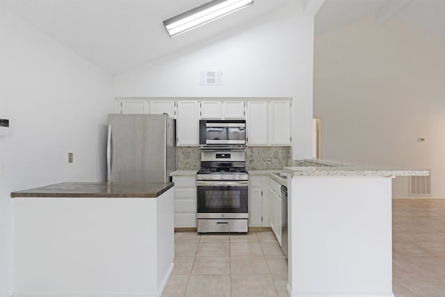 kitchen featuring visible vents, appliances with stainless steel finishes, a peninsula, light tile patterned flooring, and decorative backsplash