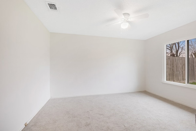 carpeted empty room with visible vents, baseboards, and a ceiling fan