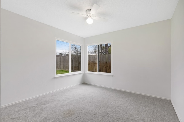 unfurnished room with a textured ceiling, a ceiling fan, baseboards, and carpet floors