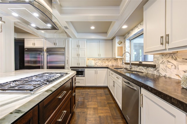 kitchen with a sink, decorative backsplash, built in appliances, and white cabinets