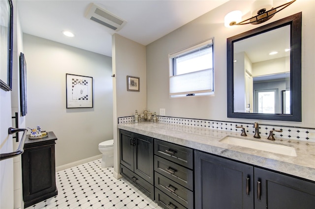 full bath with visible vents, baseboards, toilet, double vanity, and a sink