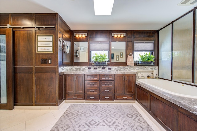 full bath with tile patterned flooring, a skylight, a bath, and vanity