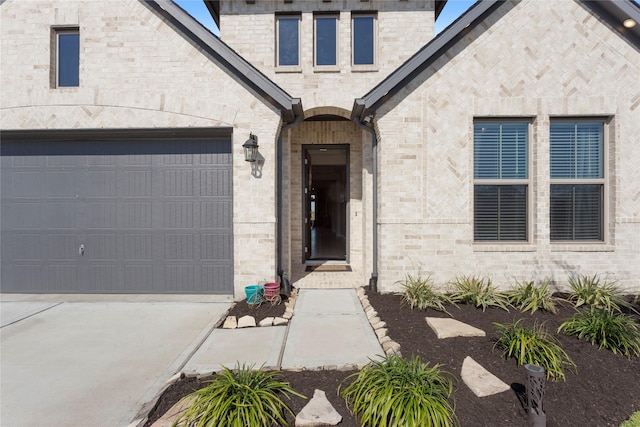 doorway to property with brick siding, driveway, and a garage