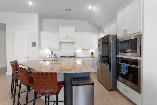 kitchen featuring visible vents, a sink, tasteful backsplash, white cabinetry, and appliances with stainless steel finishes