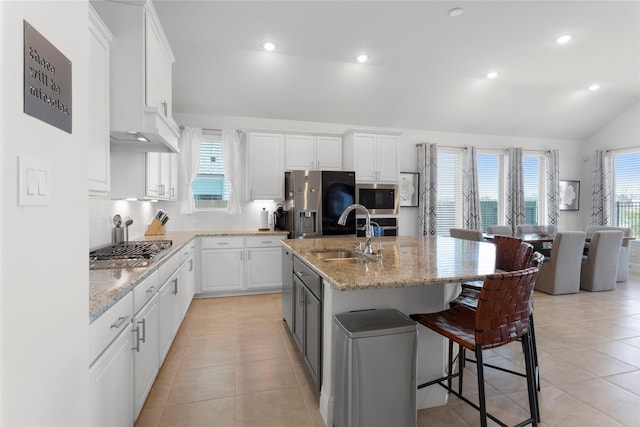 kitchen featuring a wealth of natural light, a kitchen breakfast bar, stainless steel appliances, white cabinetry, and a sink