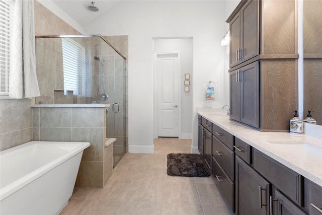 full bath featuring a sink, a shower stall, double vanity, lofted ceiling, and a soaking tub