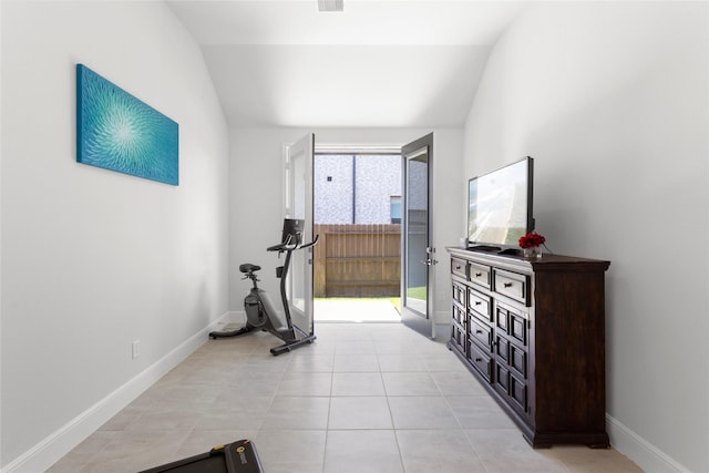 exercise area with light tile patterned floors, baseboards, and vaulted ceiling