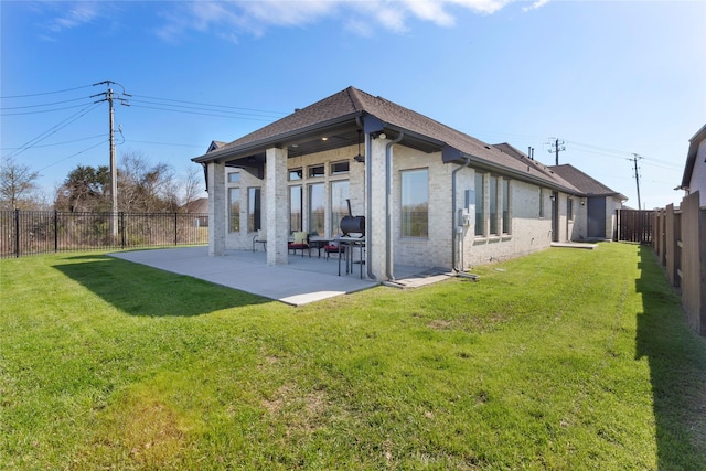 rear view of property with a patio area, a lawn, brick siding, and a fenced backyard