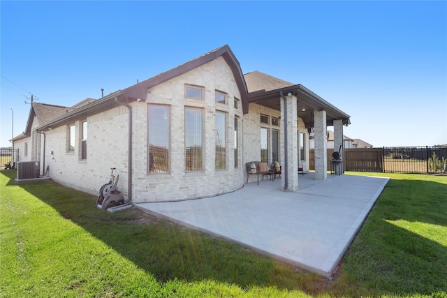 back of property featuring brick siding, a yard, a patio area, and fence