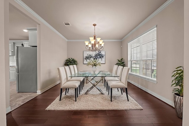 dining space featuring visible vents, baseboards, wood finished floors, and crown molding