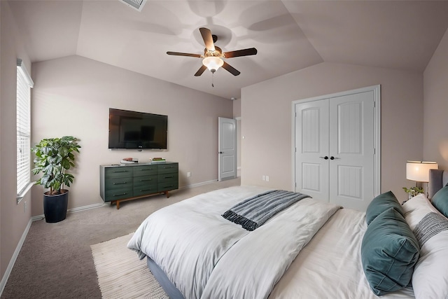 bedroom featuring a closet, light colored carpet, baseboards, and vaulted ceiling