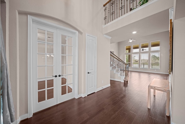 foyer entrance with wood finished floors, french doors, a high ceiling, baseboards, and stairs