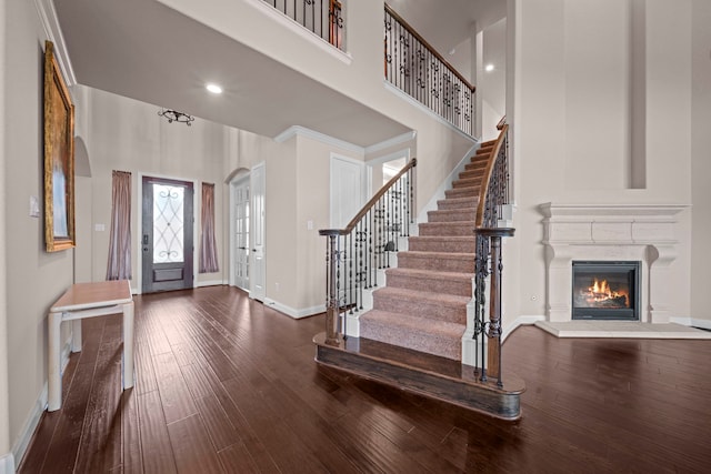 entryway featuring hardwood / wood-style flooring, stairway, baseboards, and a towering ceiling