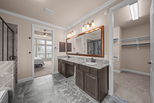 bathroom with double vanity, a stall shower, crown molding, and a sink