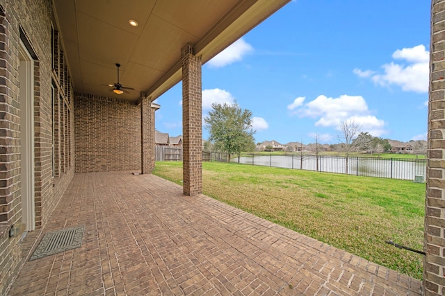 view of patio / terrace featuring a fenced backyard, a ceiling fan, and a water view