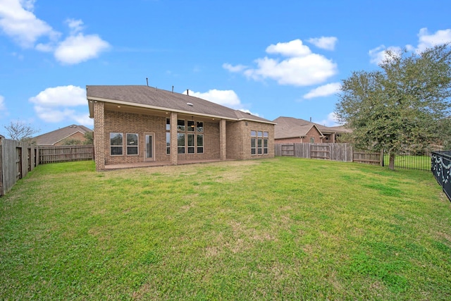 back of house featuring a yard, a fenced backyard, and brick siding