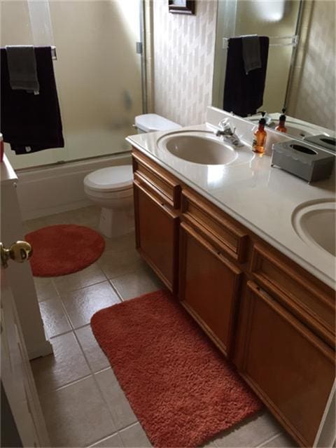 bathroom featuring a sink, bath / shower combo with glass door, double vanity, and tile patterned flooring