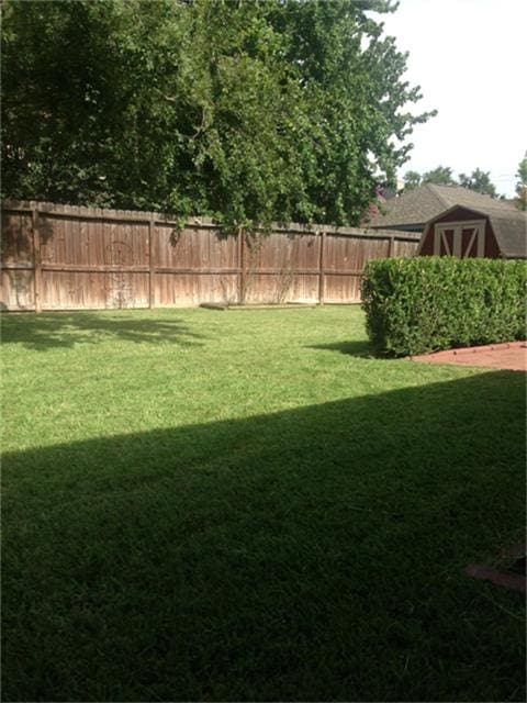 view of yard featuring an outbuilding, a storage unit, and fence