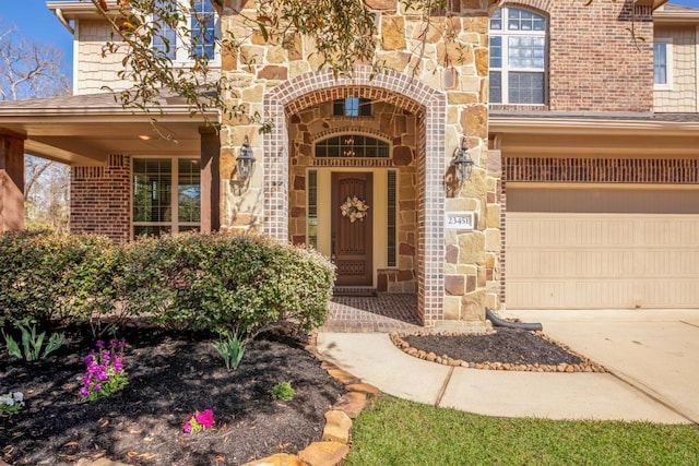 view of exterior entry with brick siding, stone siding, and driveway