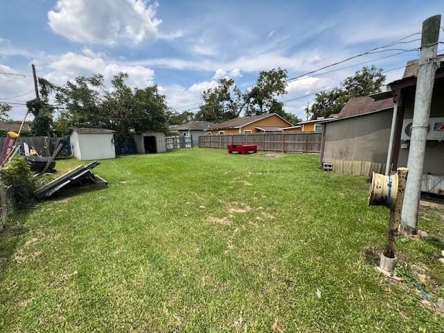 view of yard featuring an outbuilding, a storage shed, and a fenced backyard