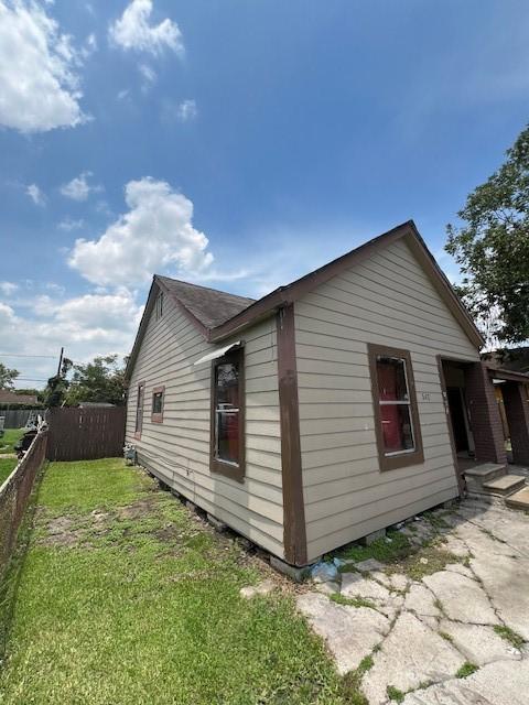 view of side of property featuring a lawn and fence