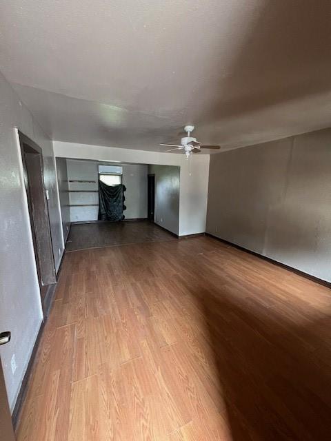 unfurnished living room with dark wood-type flooring and a ceiling fan