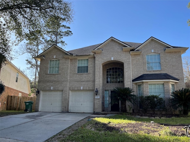 traditional home with brick siding, an attached garage, concrete driveway, and fence