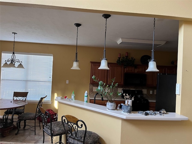 kitchen with decorative light fixtures, light tile patterned floors, black appliances, and light countertops