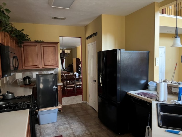 kitchen featuring brown cabinetry, visible vents, a sink, black appliances, and light countertops