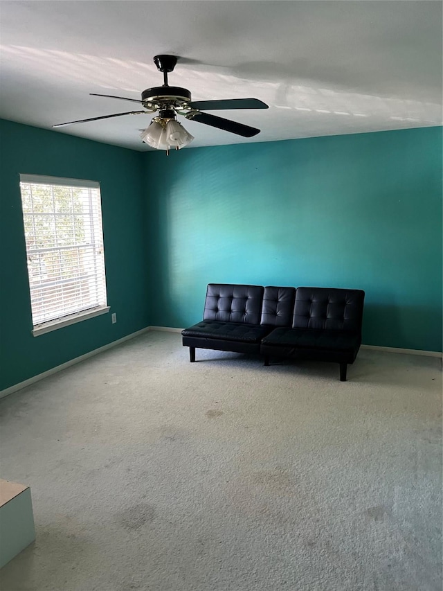 living area featuring carpet, baseboards, and ceiling fan