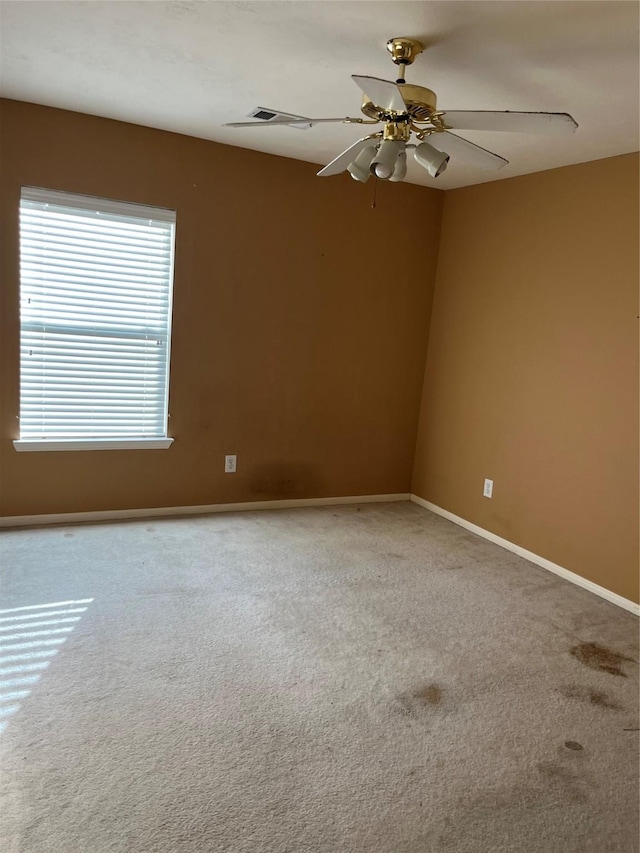 carpeted empty room with a ceiling fan and baseboards