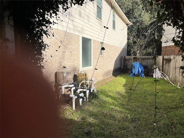 exterior space with brick siding, a lawn, and fence