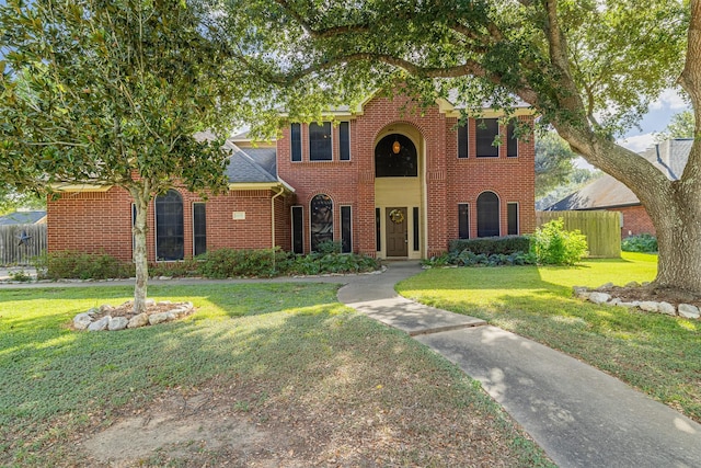 view of front of home with a front yard, fence, and brick siding