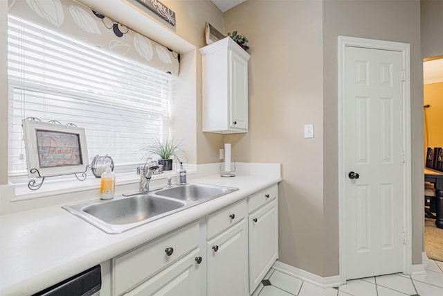 kitchen with a sink, white cabinetry, light countertops, dishwashing machine, and baseboards