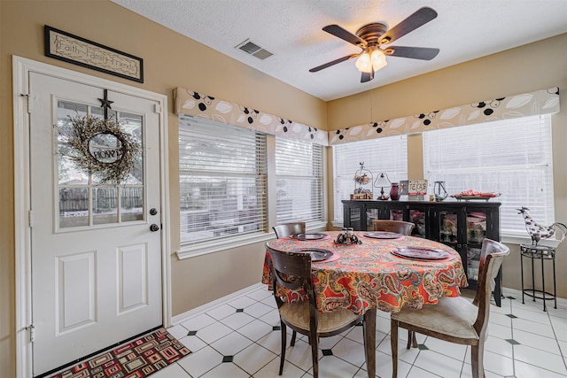 dining area featuring plenty of natural light, a textured ceiling, visible vents, and a ceiling fan