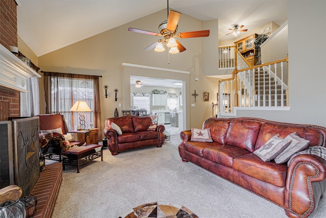 carpeted living room with ceiling fan, stairway, a fireplace, and high vaulted ceiling