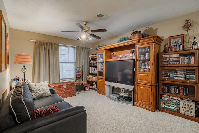 living room with visible vents, light colored carpet, a ceiling fan, and a textured ceiling