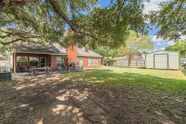 back of property featuring a patio, a shed, a fenced backyard, an outdoor structure, and brick siding