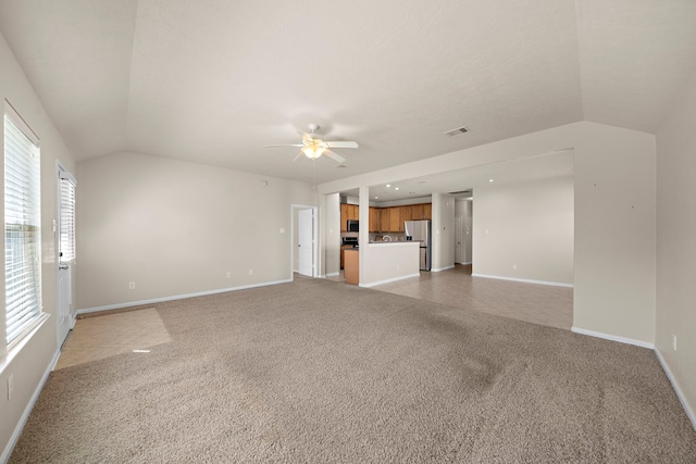 unfurnished living room with lofted ceiling, light colored carpet, and baseboards