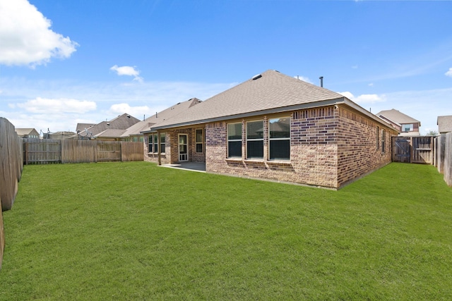 rear view of house featuring brick siding, a fenced backyard, a lawn, and a shingled roof