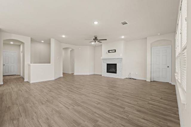 unfurnished living room featuring a glass covered fireplace, ceiling fan, light wood-type flooring, and visible vents