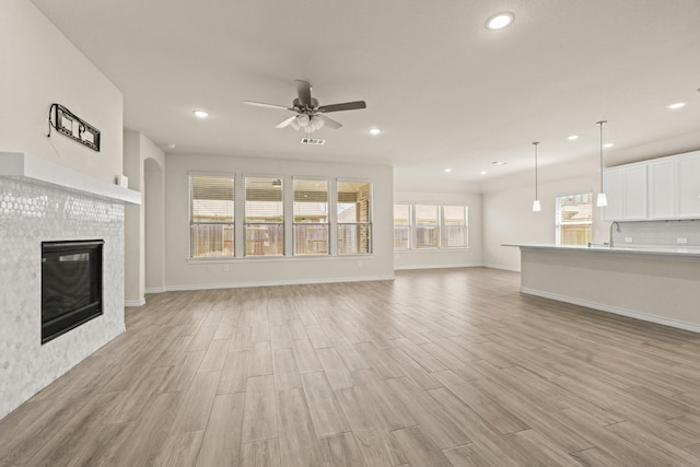 unfurnished living room with recessed lighting, light wood-style flooring, a fireplace, and a ceiling fan