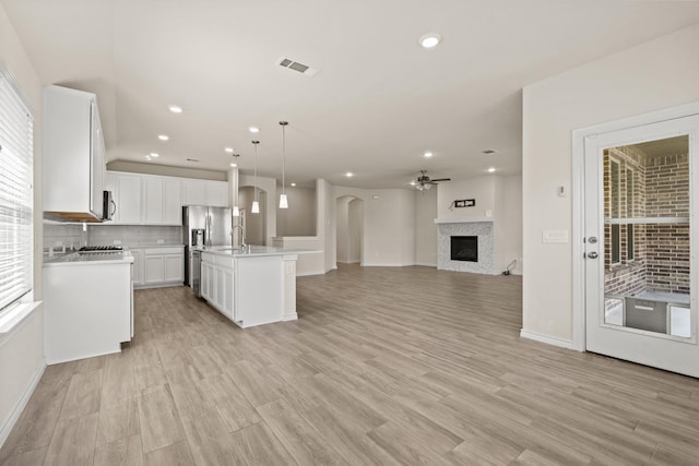 kitchen featuring visible vents, a fireplace, light countertops, open floor plan, and backsplash