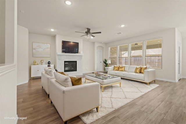 living area featuring recessed lighting, visible vents, a glass covered fireplace, and light wood-style flooring