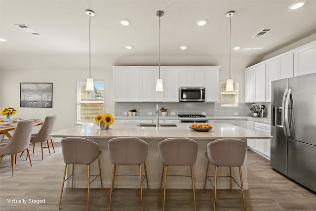 kitchen featuring tasteful backsplash, visible vents, stainless steel appliances, and a sink